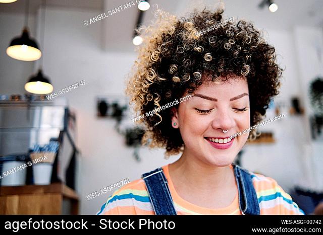 Young woman with eyes closed smiling at cafe