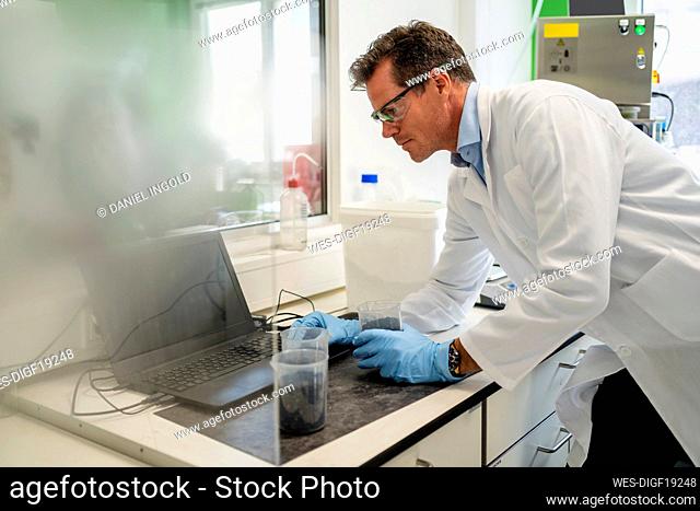 Scientist wearing lab coat using laptop in laboratory