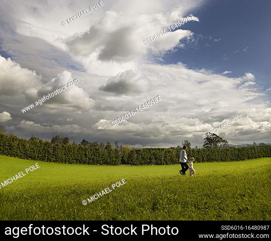 Pregnant mother and little girl walking through field together