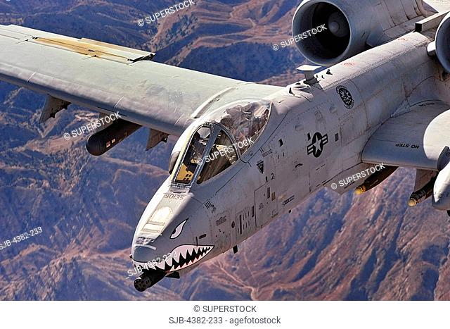 A close-up view of an A-10 Thunderbolt II, also known as a Warthog, in flight over Afghanistan. The cockpit and front-mounted machine-gun are clearly visible
