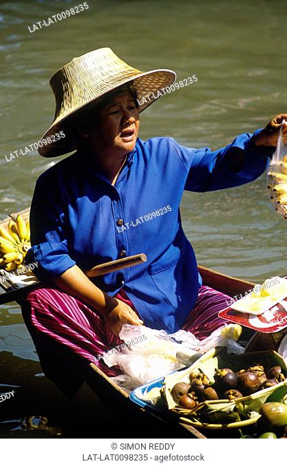 Damnoen Saduak. Ratchaburi. Woman in hat seated in boat. Selling fruit