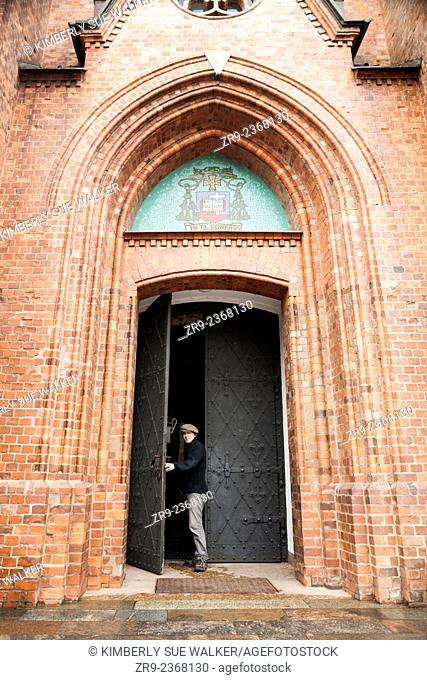 Man exits the arched doorway of the Gothic Revival styled St. Florian Cathedral, Praga district, Warsaw, Poland, Central Europe