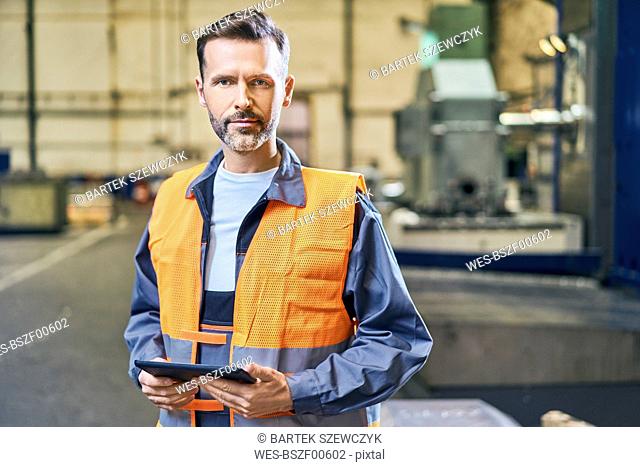 Portrait of man holding tablet in factory