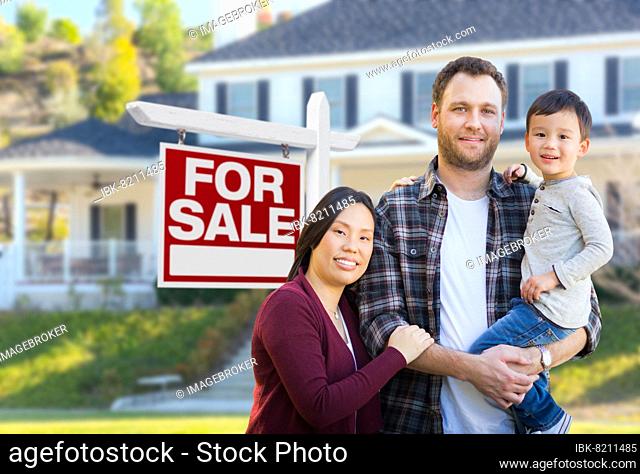mixed-race chinese and caucasian parents and child in front of house and for sale real estate sign