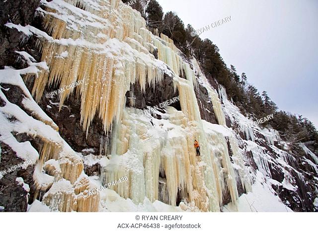 A man climbs a steep, colorful ice climb, Aurorae WI 4+, near St. Raymond, Quebec, Canada