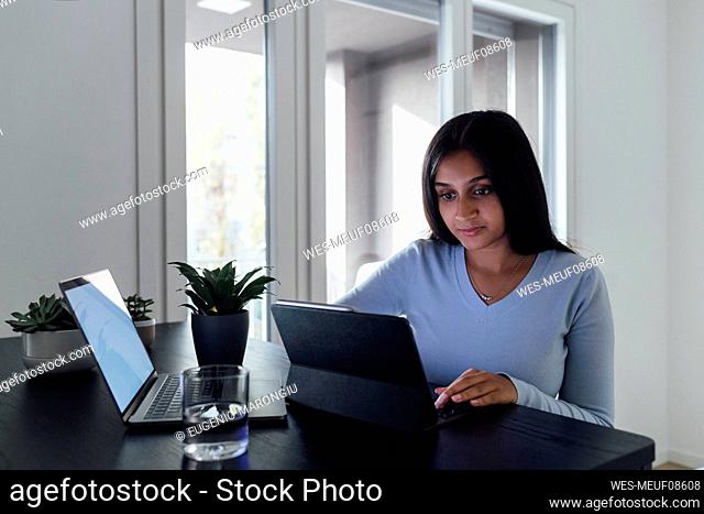 Young woman studying through laptop at home