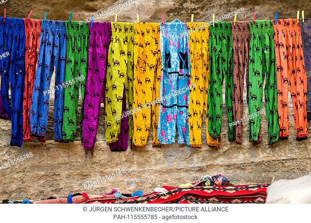 In the rock town of Petra, a trader offers for sale colourful and light cotton trousers which he has hung on a leash. (05 November 2018) | usage worldwide