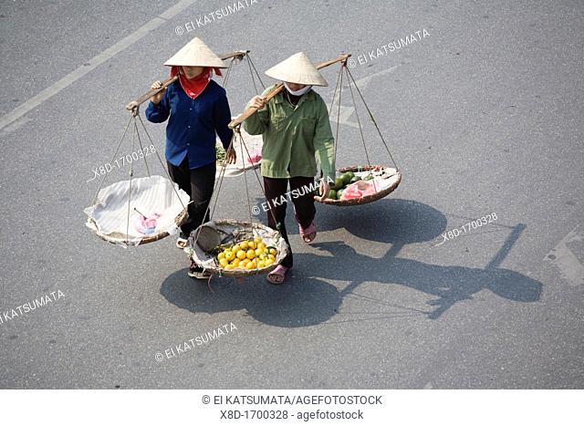Street vendors with baskets crossing the street, Old Quarter, Hanoi, Vietnam
