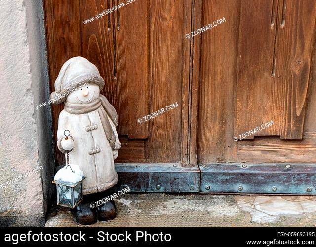 close up of a wooden door and entry with an inviting and decorative Christmas statue in the corner during the holiday season