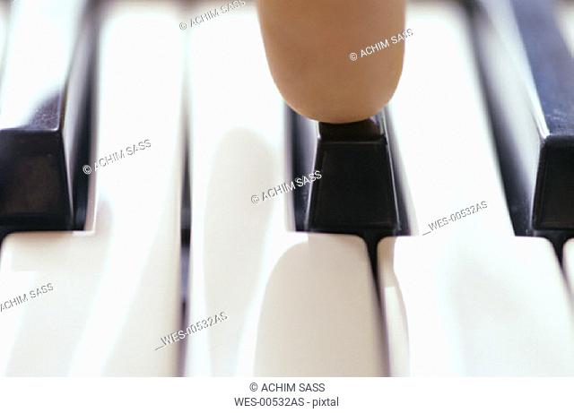 Human finger on piano keys, close up