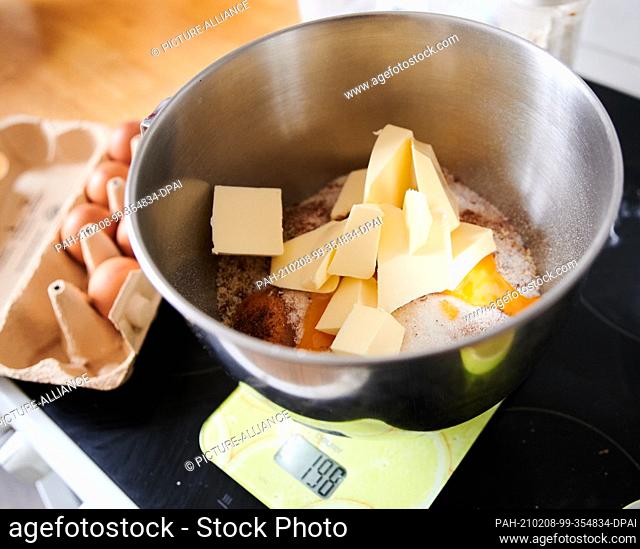 04 February 2021, Berlin: In a bowl is butter, egg yolks, flour, ground almonds, cinnamon and clove powder. The bowl is on a kitchen scale next to eggs