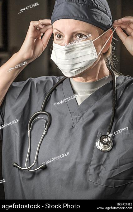 Female doctor or nurse with stethoscope putting on protective face mask