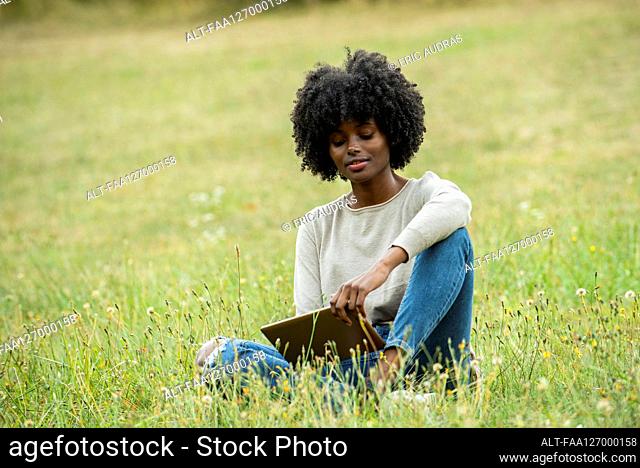Young woman using digital tablet in public park