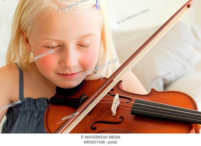 A girl plays the violin and listens to her music with her eyes closed