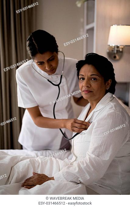 Nurse examining patient on bed at home