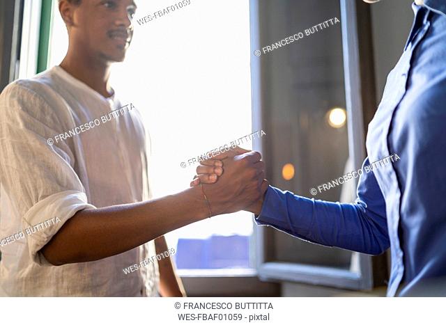 Happy young man high fiving with colleague in a cafe