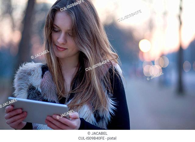 Young woman using digital tablet in street, London, UK
