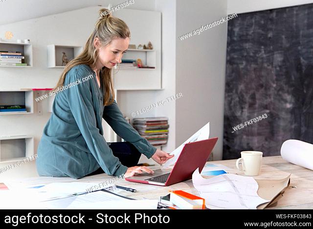 Woman using laptop on desk in home office