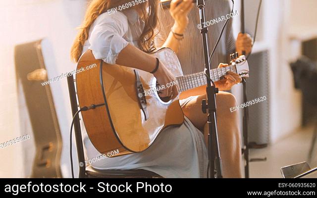 Woman with guitar at stage in loft - rock band - hipster's music