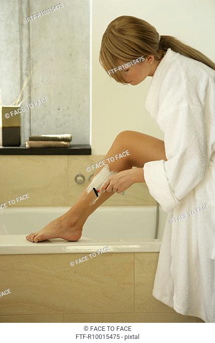 A blonde woman using an epilator on her leg