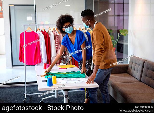 Diverse male and female fashion designers at work discussing and looking at clothes