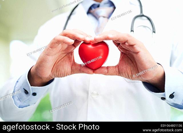 Asian woman doctor holding red heart for health in hospital
