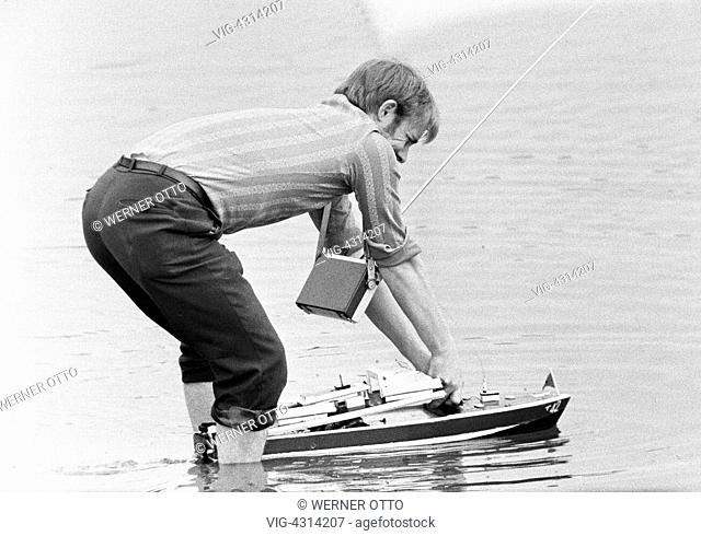 DEUTSCHLAND, BOTTROP, 07.08.1972, Seventies, black and white photo, people, man stands with his feet in water starting his model ship, handheld transmitter