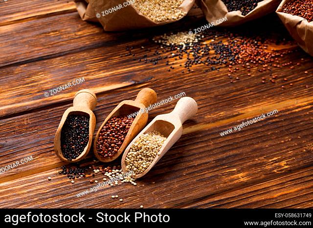 Seeds of white, red and black quinoa in wooden scoops close up