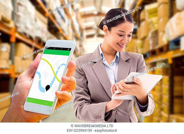 Hand holding smartphone against shelves with boxes in warehouse