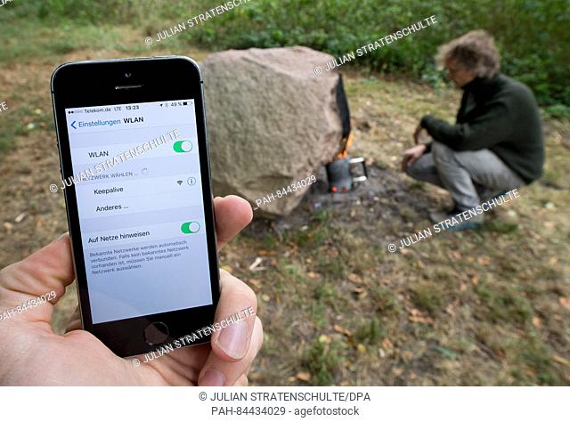 A smartphone is held up next to the installation 'Keepalive' by artist Aram Bartholl in a forest near Neuenkirchen,  Germany, 28 September 2016