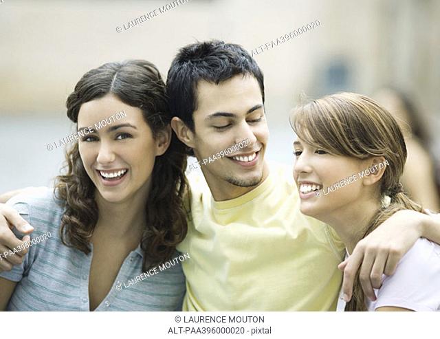 Teen boy with arms around two female friends