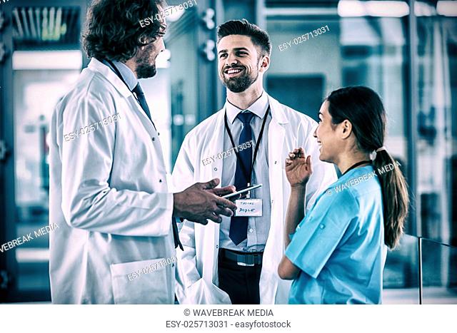 Doctor holding digital tablet having discussion with colleagues