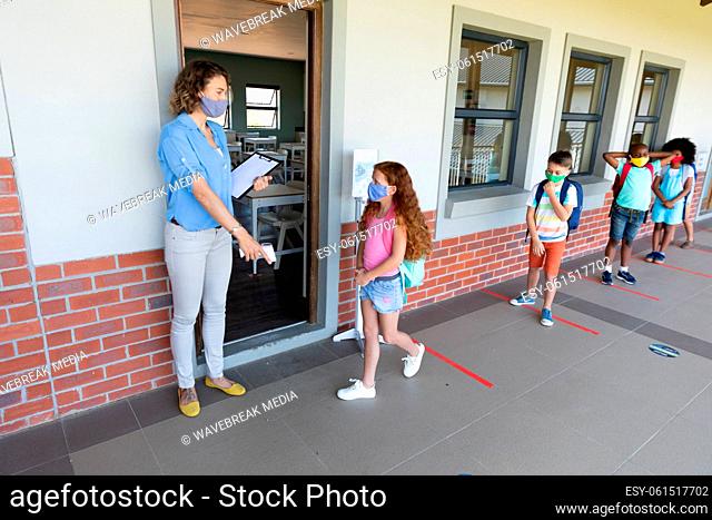 Female teacher wearing face mask pointing girl to stand on the marker