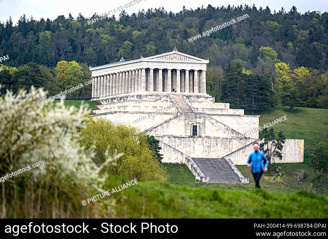 14 April 2020, Bavaria, Donaustauf: A woman is jogging in front of the Walhalla near Regensburg. The Walhalla was designed by Leo von Klenze and built between...