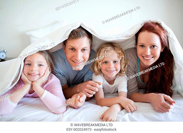 Happy smiling family under bed cover
