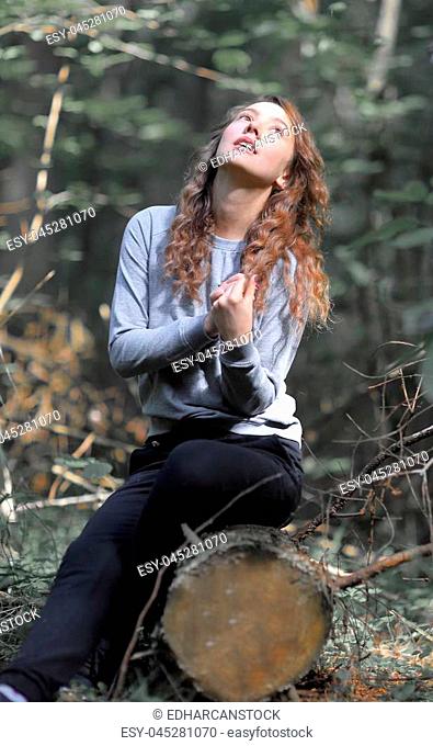 portrait of beautiful young woman sitting on a log in the woods