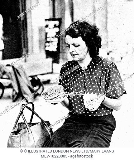 Photograph showing a German woman in Berlin holding her daily ration: a small piece of bread, a few carrots and some dehydrated potatoes, August 1945