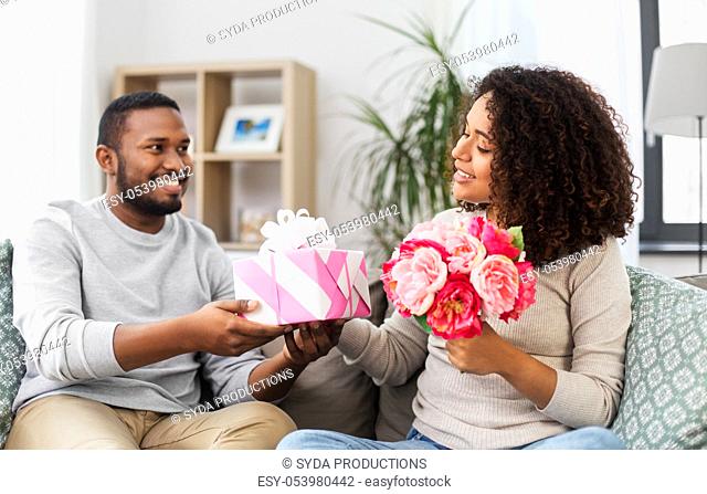 happy couple with flowers and gift at home