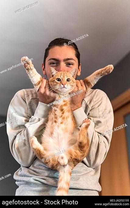 Young man playing with cat at home