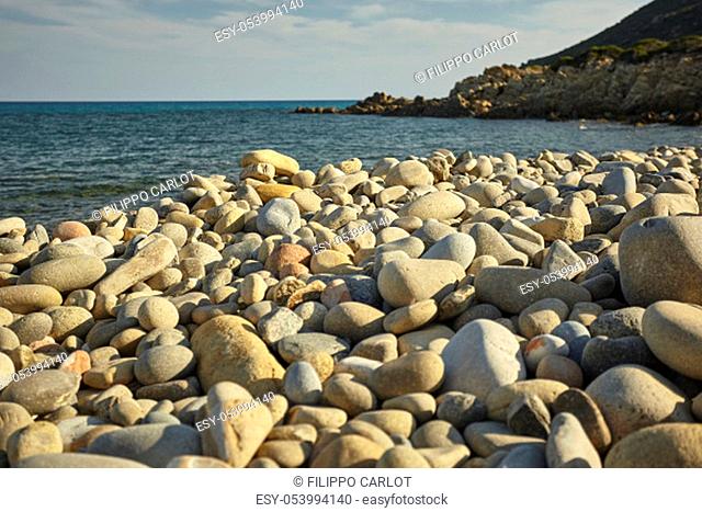 Detail of some white pebbles on a typical beach of the southern coast of southern Sardinia in Italy, with the background of the rest of the beach and the sea