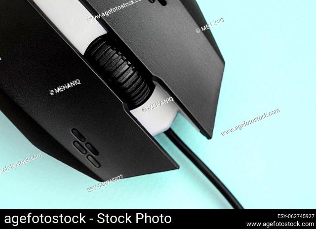 Closeup of a black gaming optical mouse on a blue background. Device for cybersport and online video games