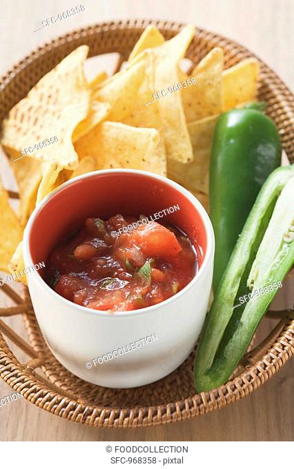Tomato salsa, nachos and fresh chilli in basket