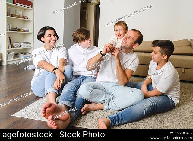 Cheerful family sitting on carpet in living room at home
