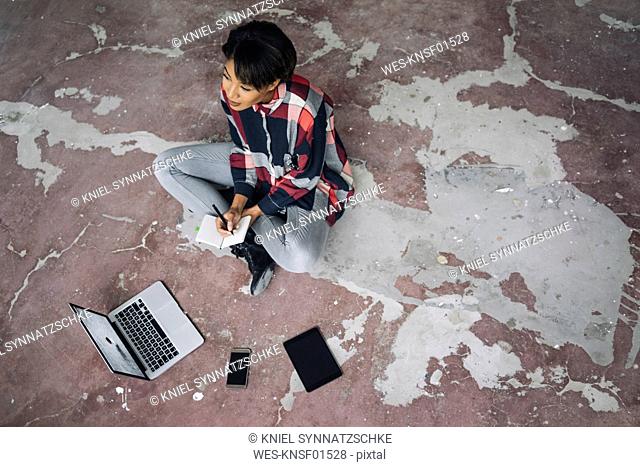 Woman sitting on cracked floor with notebook