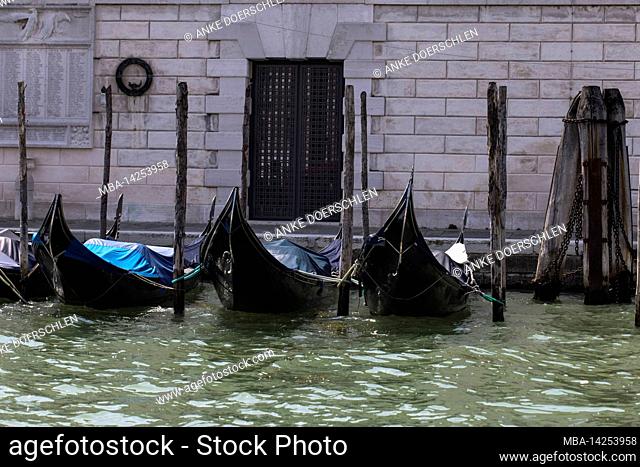 Three gondolas on wooden poles in Venice