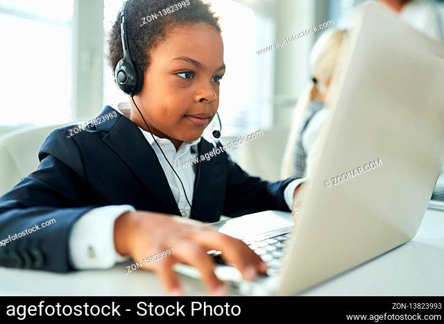 Afrikanisches Kind als Geschäftsmann am Laptop Computer in einer Videokonferenz