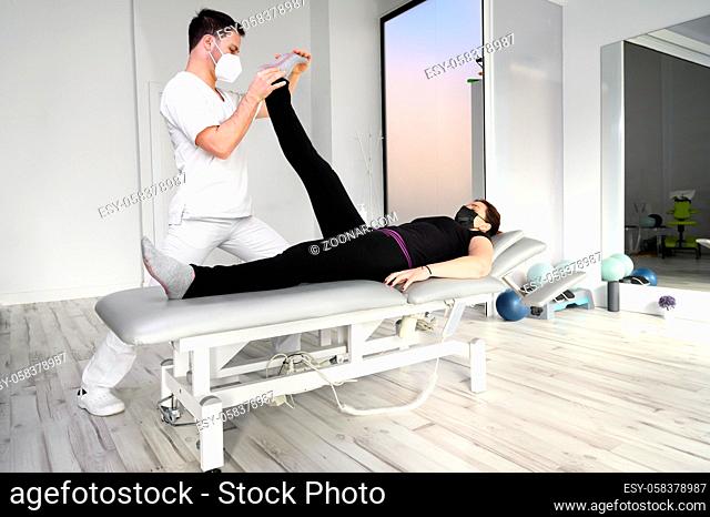 physiotherapist doing leg muscle stretching to female patient. Treatment of a woman's sciatic nerve. High quality photo