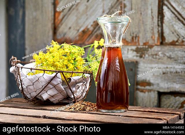 working steps with fennel and fennel seeds for the preparation of fennel syrup, wire basket with fennel flowers and weck bottle with fennel syrup on a wooden...