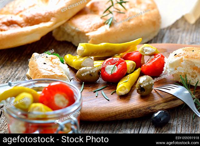 Griechischer Imbiss bestehend aus Oliven sowie Peperoni und Kirschpaprikas gefüllt mit Frischkäse, dazu Fladenbrot ? Greek snack