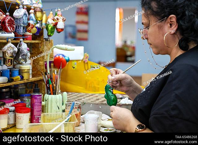RUSSIA, KRASNOYARSK - DECEMBER 5, 2023: A woman paints baubles at Biryusinka, an enterprise producing handmade Christmas decorations